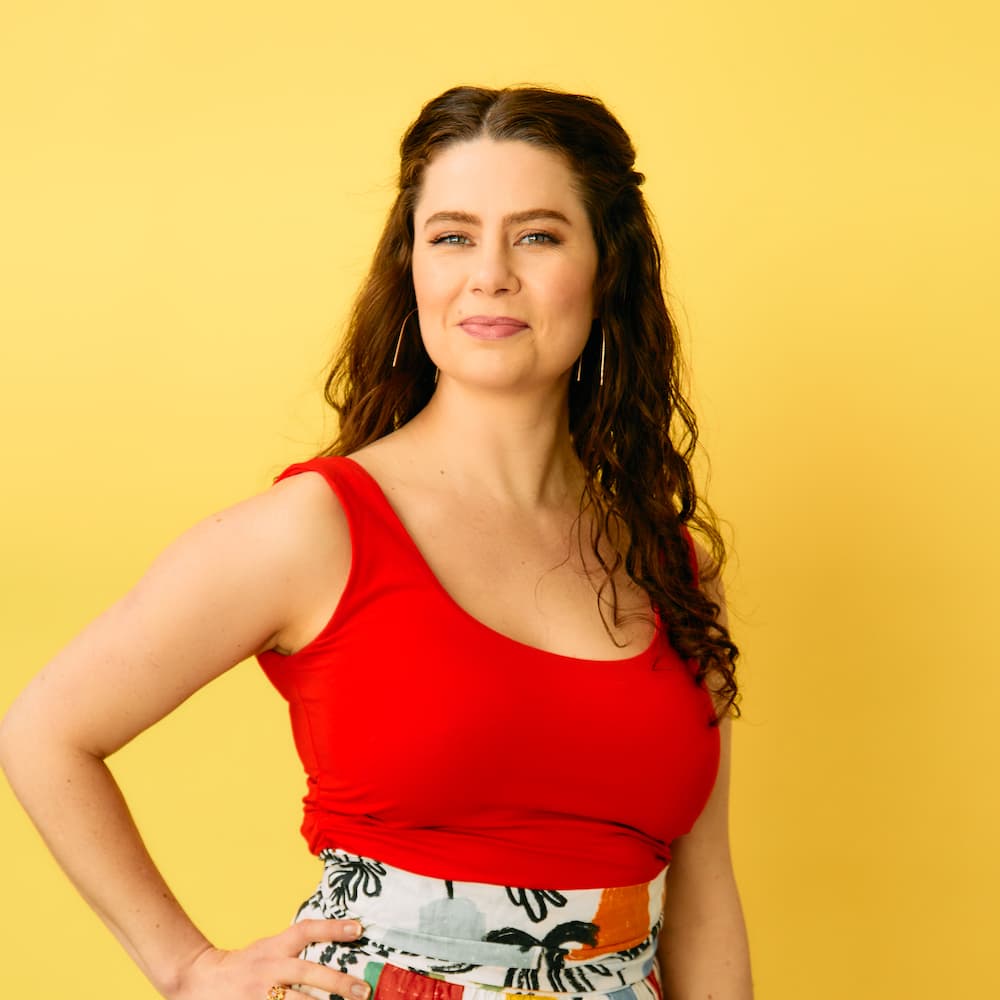 closeup portrait of Kaitlin Carpenter wearing a bright orange shirt and grinning